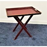 BUTLERS TRAY on a folding stand, the claret tray with raised sides and inset handles, 55.5cm wide