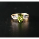 PERIDOT AND DIAMOND RING the oval cut peridot approximately 1ct flanked by two small diamonds to