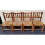 SET OF FOUR RUSTIC PINE DINING CHAIRS with bow shaped backs with turned columns above woven rush