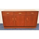 G PLAN TEAK SIDE CABINET with three frieze drawers above three cupboard doors, standing on a