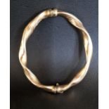 NINE CARAT GOLD BANGLE of twisted design and with safety clasp, approximately 10.6 grams