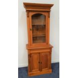 LARGE LIGHT TEAK SIDE CABINET with a moulded cornice above an arched glazed door opening to reveal