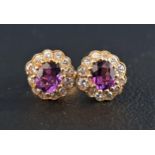 PAIR OF AMETHYST AND DIAMOND CLUSTER EARRINGS each stud earring with central oval cut amethyst of
