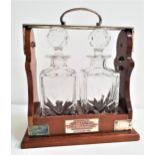 MAHOGANY TANTALUS with silver plated mounts and two decanters with stoppers, with a presentation