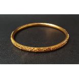 TWENTY-TWO CARAT GOLD BANGLE with relief detail, approximately 10.3 grams