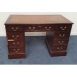 MAHOGANY KNEEHOLE DESK with an inset leather top above an arrangement of seven drawers and a small