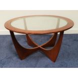 G PLAN TEAK ASTRO OCCASIONAL TABLE with a circular glass inset top, standing on shaped supports,