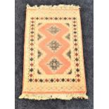 PAKISTAN BOKHARA RUG with a pink ground with lozenge motifs, encased by a geometric border, fringed,