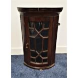 19th CENTURY MAHOGANY BOW FRONT CORNER CUPBOARD with a moulded dentil pediment above an astragal
