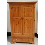 WAXED PINE WARDROBE with a pair of panelled doors opening to reveal hanging space, with a panelled