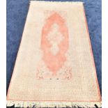 TABRIZ RUG with a coral ground with a central medallion, encased by a multi layered border, fringed,