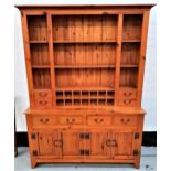 WAXED PINE DRESSER with a moulded top above three central drawers and fourteen bottle holders,