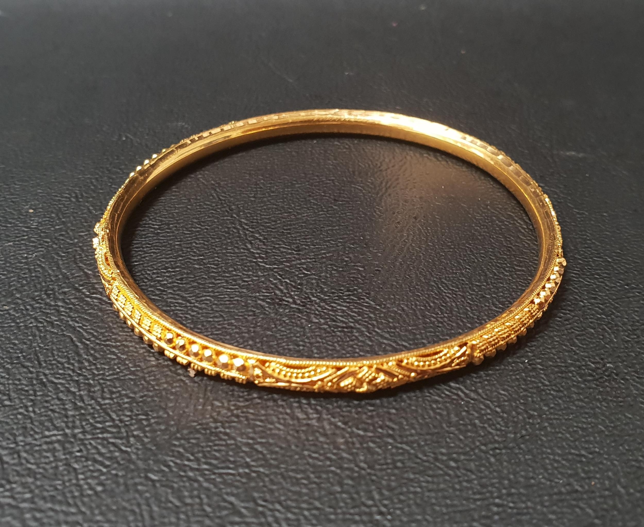 TWENTY-TWO CARAT GOLD BANGLE with relief detail, approximately 10 grams