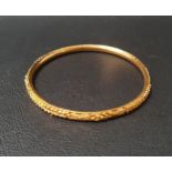 TWENTY-TWO CARAT GOLD BANGLE with relief detail, approximately 10 grams