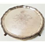 GEORGE V SILVER PRESENTATION SALVER with a scalloped decorative border, raised on four hoof feet,