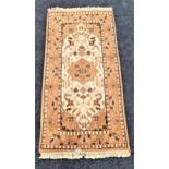 PERSIAN RUG with a cream and tan ground encased by a floral border, fringed, 145cm x 69cm