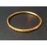 TWENTY-TWO CARAT GOLD BANGLE with relief detail, approximately 9.9 grams