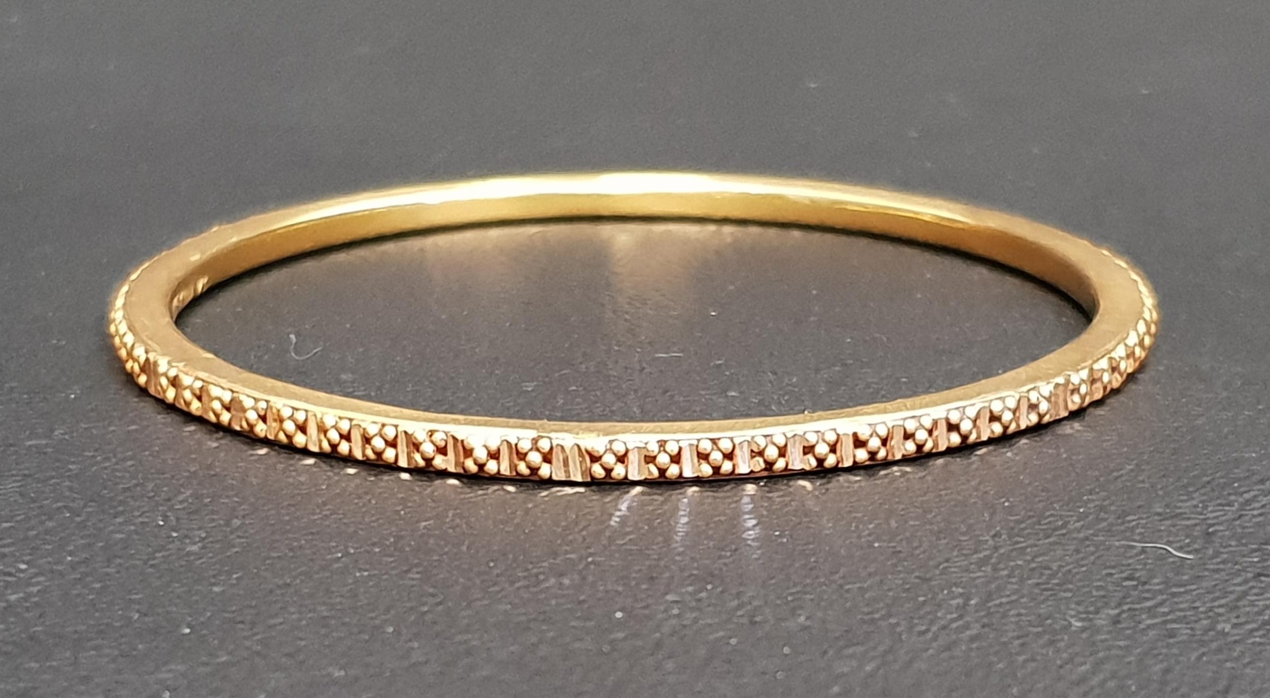 TWENTY-ONE CARAT GOLD BANGLE with relief ball detail, approximately 7.8 grams