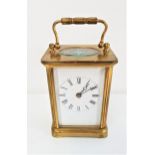 BRASS CARRIAGE CLOCK with an enamel dial with Roman numerals, bevelled glass panels and a fold