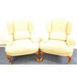 PAIR OF WING BACK ARMCHAIRS with scroll arms above loose shaped seat and back cushion, standing on