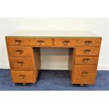 ERCOL LIGHT ELM KNEEHOLE DESK with an arrangement of eight drawers, on later casters, 118cm wide