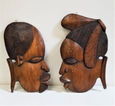 AFRICAN CARVED TEAK WALL PLAQUE of a male and female head in profile, 47cm and 45cm high (2)