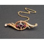 GARNET AND RUBY SET SCROLL DESIGN BROOCH in nine carat gold, the central round cut garnet flanked by