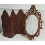 OVAL WALL MIRROR in a pierced gilt resin frame, 79cm high, together with a carved teak three fold