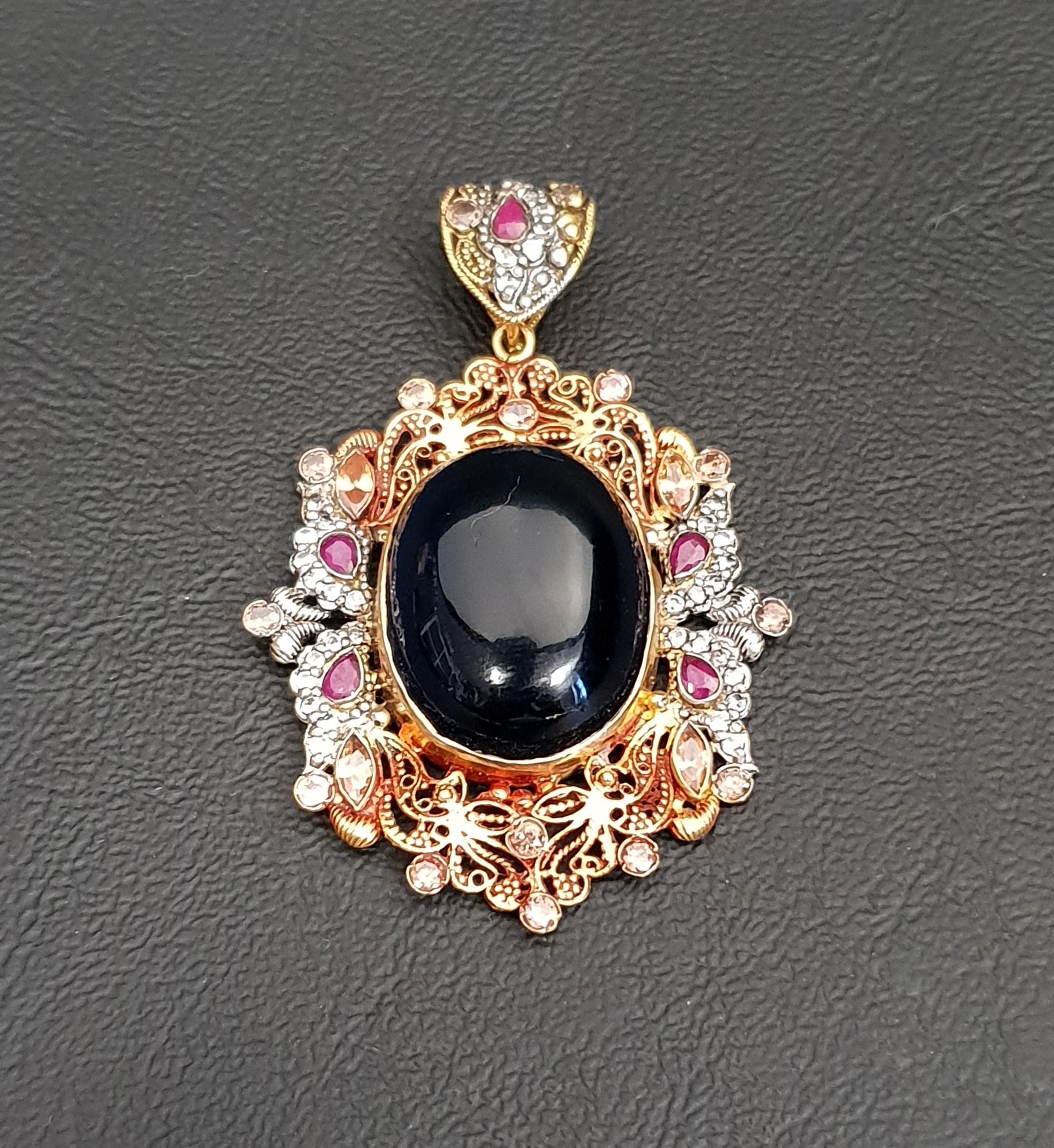 TWENTY-ONE CARAT GOLD PENDANT the central cabochon blue glass in pierced surround set with rubies