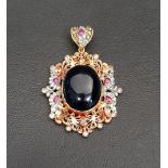 TWENTY-ONE CARAT GOLD PENDANT the central cabochon blue glass in pierced surround set with rubies