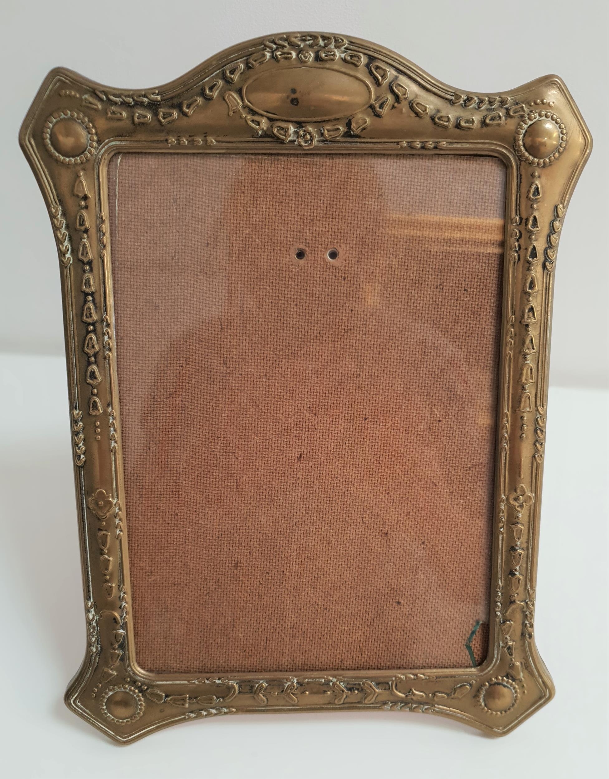 EARLY 20th CENTURY BRASS EMBOSSED PHOTOGRAPH FRAME decorated with swags of husks, with a fold out