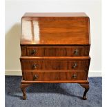 WALNUT AND CROSSBANDED BUREAU with a fall flap opening to reveal a fitted interior above three