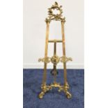 GILT BRASS EASEL decorated with scrolls, with an adjustable front stand, 119.5cm high