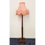 1930s WALNUT STANDARD LAMP raised on a shaped base with four ribbed feet, with a shaped turned