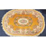 OVAL CHINESE WASH RUG with a yellow ground and centred with floral motifs and encased by a floral