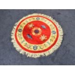 CHINESE CIRCULAR WASH RUG with a red ground and cream floral border, fringed, 126cm diameter