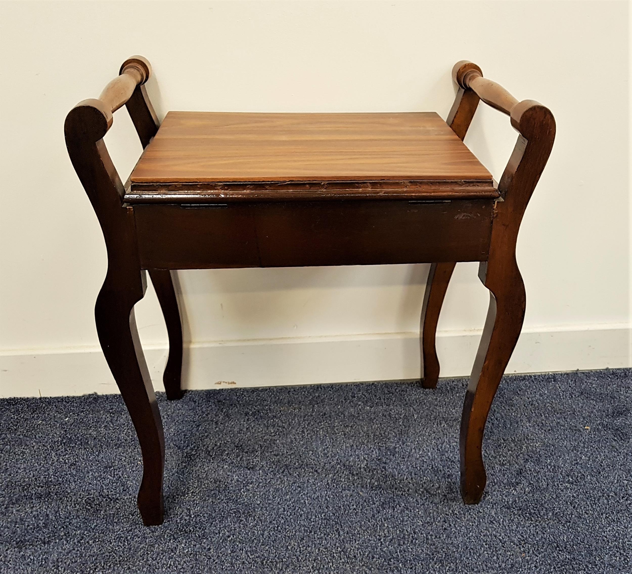 EDWARDIAN MAHOGANY PIANO STOOL with a lift up seat flanked by turned handles, standing on shaped