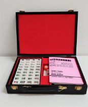 CASED MAH-JONGG SET with hard plastic tiles and dice, with instruction booklet, in an atache style