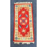 CHINESE RECTANGULAR WASH RUG with a red ground and cream border with Chinese motifs, fringed,