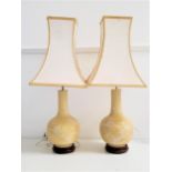 PAIR OF CHINESE STYLE BOTTLE LAMPS with a pale yellow ground and decorated with birds in a tree,