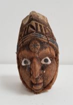 20th CENTURY CARVED COCONUT decorated with a face with painted shell eyes below the word Trinidad,