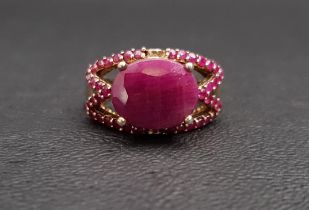 RUBY DRESS RING the central oval cut ruby surrounded by smaller rubies to the pierced setting, in