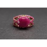 RUBY DRESS RING the central oval cut ruby surrounded by smaller rubies to the pierced setting, in