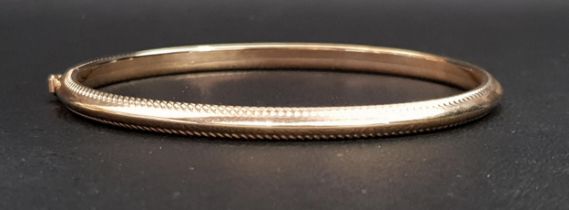 NINE CARAT GOLD BANGLE with ribbed edge detail and safety clasp, approximately 4.3 grams