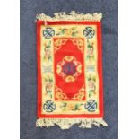 CHINESE RECTANGULAR WASH RUG with a red ground and cream border, fringed, 95cm x 63cm excluding