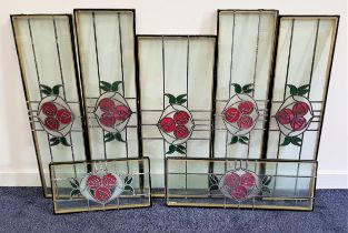 SEVEN DOUBLE GLAZED WINDOW PANELS each with a leaded stained glass design in the Glasgow style, of