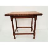 OAK GAMES TABLE with a baize lined fold over top, standing on turned supports united by a stretcher,