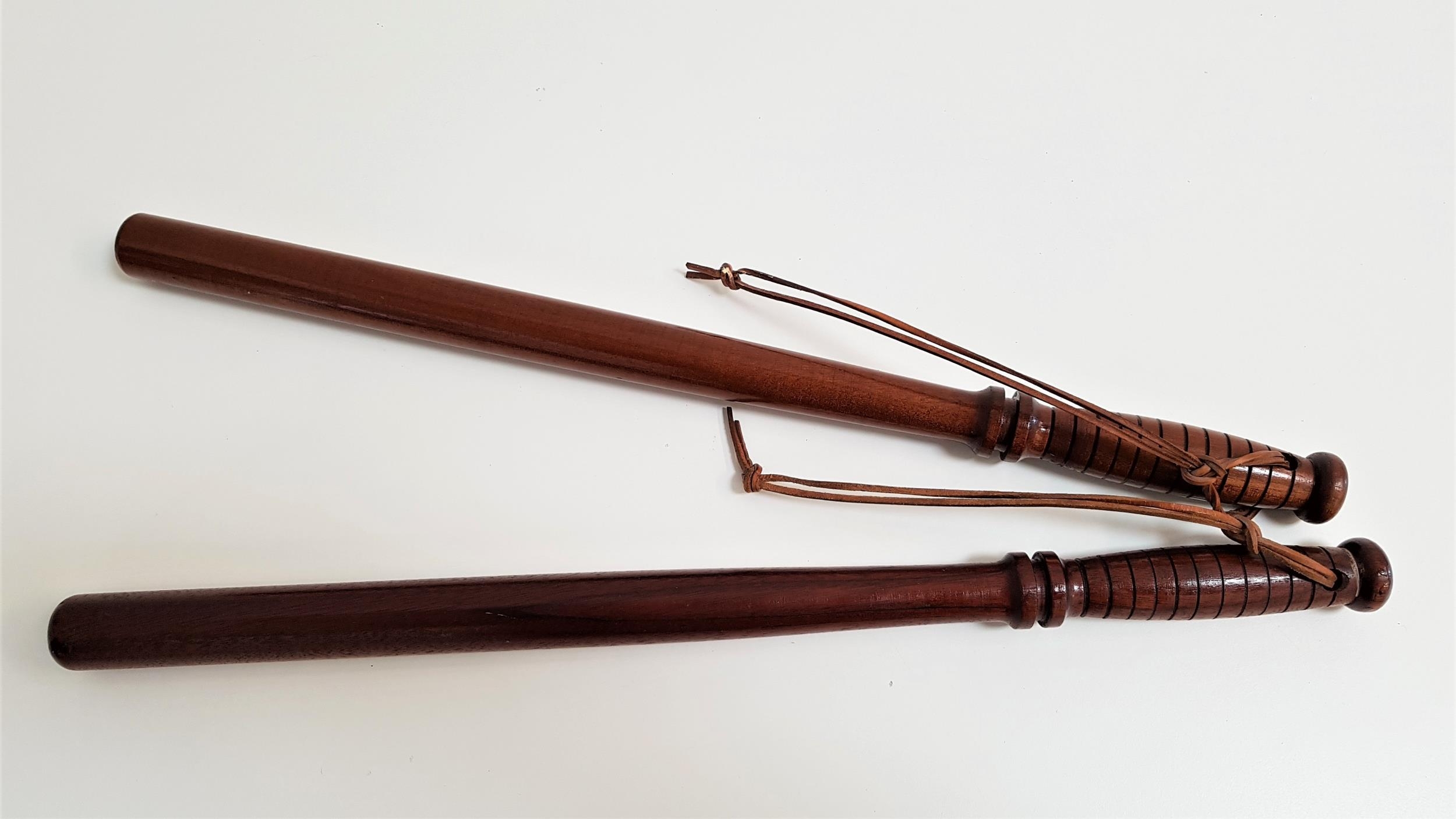 TWO MAHOGANY TRUNCHEONS with turned ribbed handles and leather wrist straps, each 55.5cm long (2)