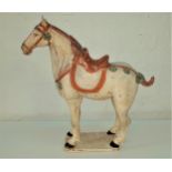 POTTERY TANG STYLE HORSE with a detailled head collar and saddle, on a rectangular plinth, 52.5cm