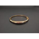 EDWARD VII RED GEM AND SEED PEARL NINE CARAT GOLD BANGLE the hinged bangle with rope twist detail